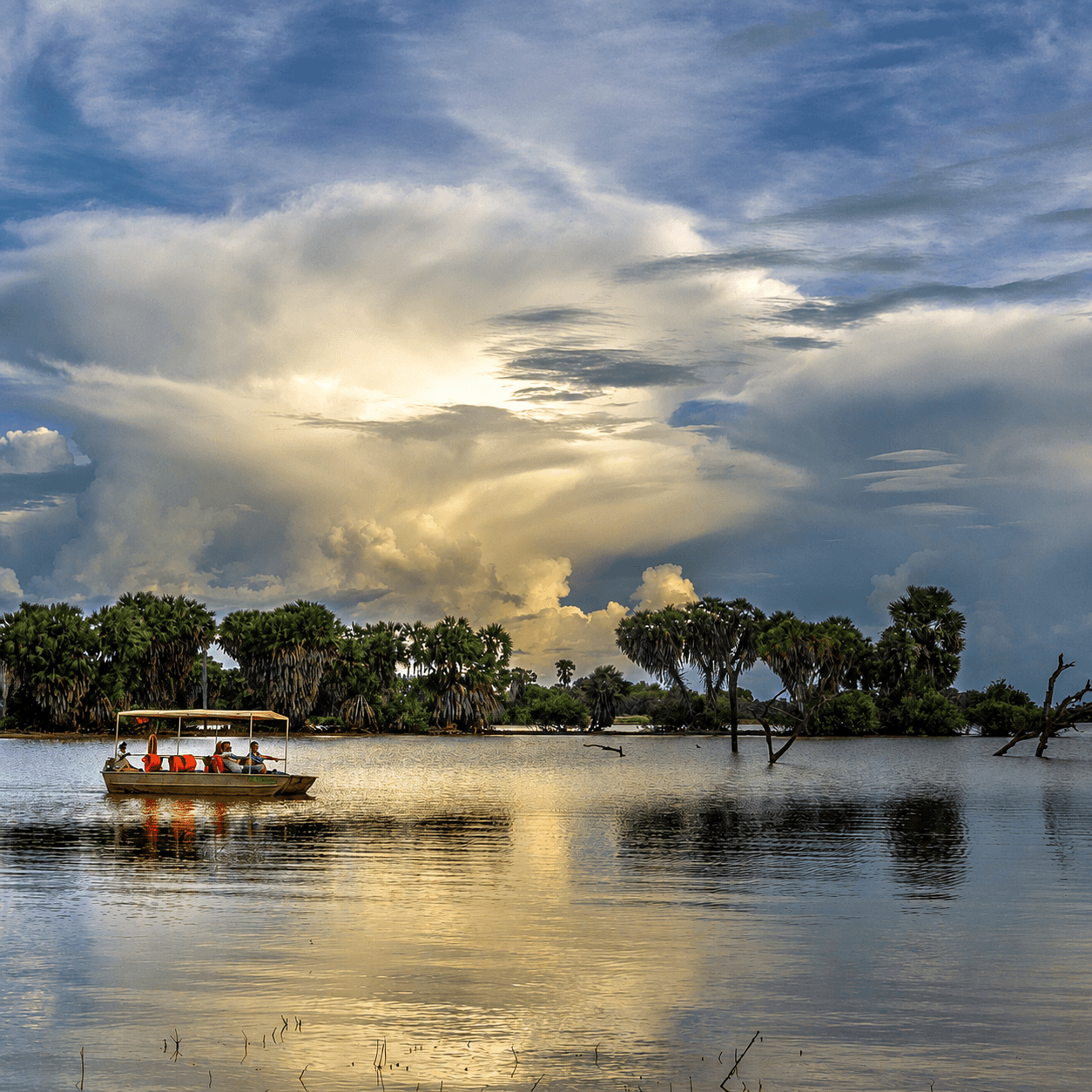 A safari boat crossing the Rufiji River beneath a dramatic sky in Nyerere